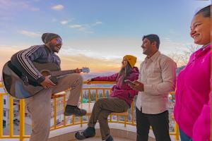 a group of people standing on a balcony playing guitar at The Hosteller Narkanda in Nārkanda
