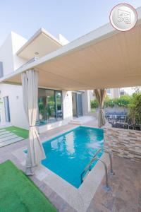 a swimming pool in a house with an umbrella at 5 bedroom Villa - Dubai Hills in Dubai