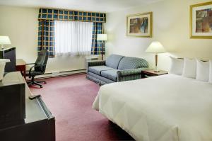 a hotel room with a bed and a chair and a couch at Travelodge by Wyndham Ottawa East in Ottawa +35 photos