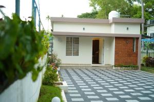 a small white house with a driveway at MARARI FARM HERITAGE INN in Mararikulam