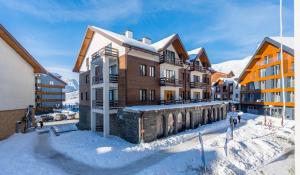 a building in the snow next to some buildings at Panorama Apartments New Gudauri in Gudauri