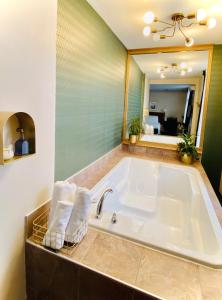Maison Cartier Montreal في مونتريال: حمام مع حوض استحمام مع المناشف ومرآة