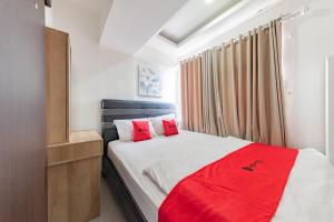 a bedroom with a bed with two red pillows at RedDoorz Apartment @ Jarrdin Cihampelas in Bandung