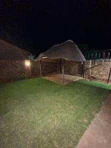 uma parede de tijolos com um guarda-chuva num quintal à noite em Townhouse on 6526 Boiketlo Street, Golfview em Mahikeng