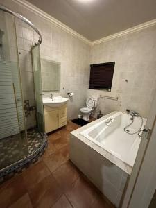 a bathroom with a tub and a shower and a toilet at Townhouse on 6526 Boiketlo Street, Golfview in Mahikeng