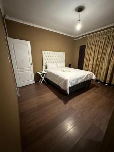 ein Schlafzimmer mit einem weißen Bett und einer Tür in der Unterkunft Townhouse on 6526 Boiketlo Street, Golfview in Mahikeng