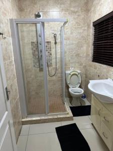a bathroom with a shower and a toilet and a sink at Townhouse on 6526 Boiketlo Street, Golfview in Mahikeng