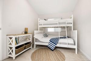 a bedroom with white bunk beds and a rug at Coorumbong 16 - 5 bedrooms in Mooloolaba +22 photos