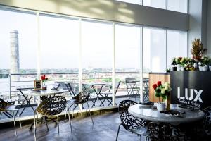 a room with tables and chairs and large windows at Menara One Hotel by Menara Santosa in Kartosuro
