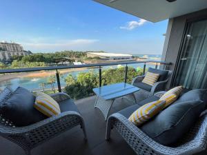 een balkon met rieten meubels en uitzicht op de oceaan bij Luxury Waterfront Stay 1bdr (breathtaking Views) in Darwin