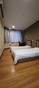 a bedroom with two beds and a wooden floor at Hotel Sadong88 in Kota Kinabalu