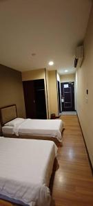 a hotel room with three beds and a hallway at Hotel Sadong88 in Kota Kinabalu