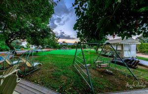 un parque con un parque infantil con un patio verde en Nuriel Fruit & Guest House, en She'ar Yashuv