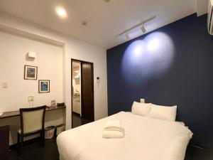 um quarto com uma cama branca e uma secretária com uma cadeira. em Luana Uakoko Resort 旧 EmiFull Resort em Chatan