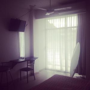 a room with a desk and a window with a television at Hotel & Suites Mo Sak in Tapachula