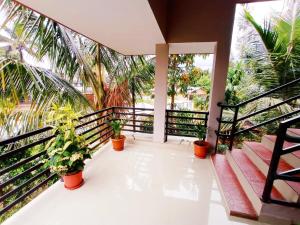 einen Balkon mit Palmen und Topfpflanzen in der Unterkunft Eve's Residency in Meppādi