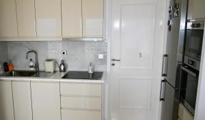 a kitchen with white cabinets and a sink and a door at Efi's Luxury Suite in Agios Nikolaos