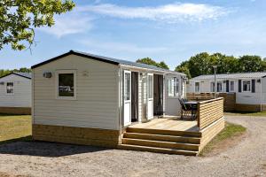 ボリホルムにあるFirst Camp Ekerum - Ölandの木製デッキ付きの小さな白い家