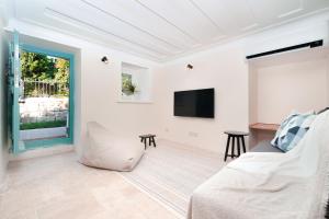 ein Wohnzimmer mit einem Sofa und einem TV in der Unterkunft MINIQ HOMES 102 - Historical Stone House with Garden Cinema in Foça