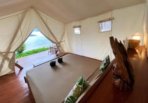 Bett in einem Zelt mit Meerblick in der Unterkunft Reconnect - Private Island Resort & Dive Center Togean - Buka Buka Island in Ampana