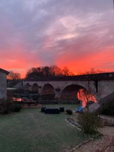 a bridge with a sunset in the background at La Rive Chambre d hôtes The Riverside Retreat in Jarnac +21 photos