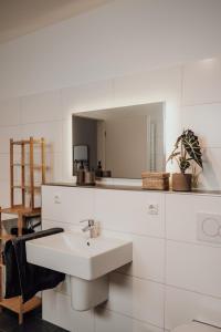 La salle de bains blanche est pourvue d'un lavabo et d'un miroir. dans l'établissement JAMA - Modern&Bright, Terrasse, Freies Parken, WLAN, Große Gruppen #1, à Wurtzbourg