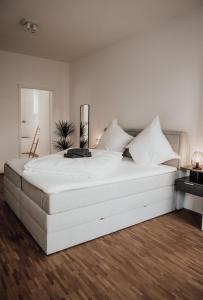 1 cama blanca grande en un dormitorio blanco con suelo de madera en JAMA - Modern&Bright, Terrasse, Freies Parken, WLAN, Große Gruppen #1 en Würzburg