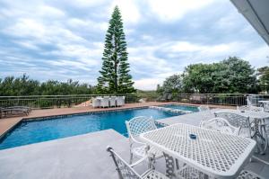 una piscina con mesas y sillas blancas y un árbol en Casabella Guesthouse, en East London
