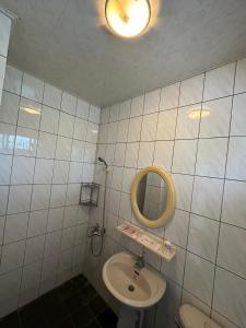 a white tiled bathroom with a sink and a mirror at Green Forest Homestay in Nung-hui-ti