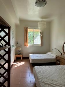 um quarto com 2 camas e uma janela em Green Forest Homestay em Nung-hui-ti