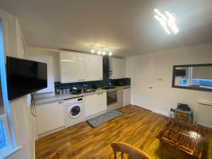 a kitchen with white cabinets and a wooden floor at cosy 1 bed flat Largs in Largs