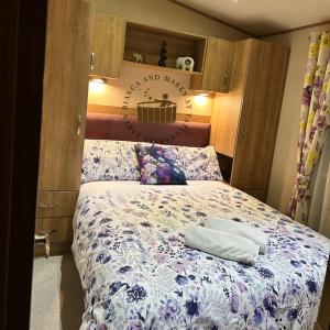 a bedroom with a bed with a floral bedspread at Bianca and marks 8 berth Caravan with Hot tub in Tattershall