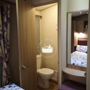 a small bathroom with a toilet and a sink at Bianca and marks 8 berth Caravan with Hot tub in Tattershall