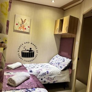 タターズホールにあるBianca and marks 8 berth Caravan with Hot tubのベッド2台付きの小さなベッドルーム1室、壁に看板が備わります。