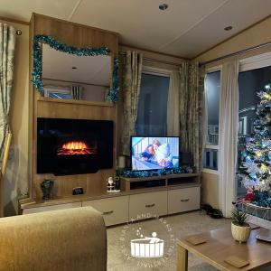 a living room with a fireplace and a christmas tree at Bianca and marks 8 berth Caravan with Hot tub in Tattershall