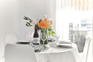 ein weißer Tisch mit einer Vase Blumen drauf in der Unterkunft lovely sunny apartment with shared pool and private parking in Torrevieja