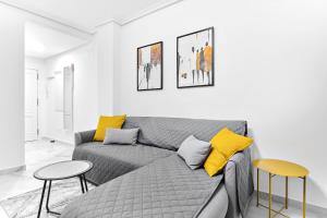 ein Wohnzimmer mit einem grauen Sofa und gelben Kissen in der Unterkunft lovely sunny apartment with shared pool and private parking in Torrevieja