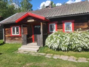 una cabaña de madera con una puerta roja en el césped en Mora Life, Åmåsängsgården, en Mora