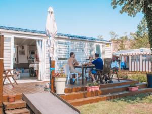 un groupe de personnes assises à une table sur une terrasse dans l'établissement Camping Les Jardins de la Mer, à Merlimont