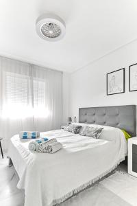 ein weißes Schlafzimmer mit einem großen Bett mit Handtüchern darauf in der Unterkunft lovely sunny apartment with shared pool and private parking in Torrevieja