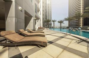 uma piscina com espreguiçadeiras ao lado de um edifício em Maison Privee - High-Floor Trendy Apt with Marina, Palm & Ocean Vws em Dubai