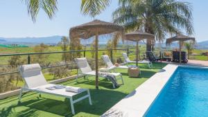 a pool with chairs and umbrellas next to a resort at Casa La Era Coin by Ruralidays in Coín