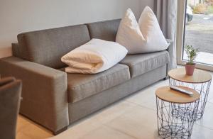 un divano con cuscini e 2 tavoli in soggiorno di Appartement Atzingerberg a Maishofen