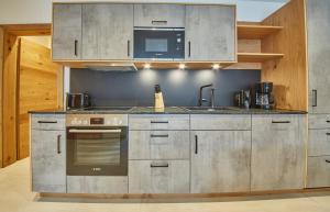 een keuken met roestvrijstalen apparatuur en een magnetron bij Appartement Atzingerberg in Maishofen