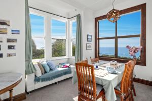 een woonkamer met een tafel, een bank en ramen bij The Professor's Beach House - Brighton Home in Mosgiel