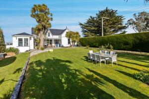 a backyard with a table and chairs on the grass at The Professor's Beach House - Brighton Home in Mosgiel