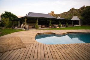 a swimming pool on a wooden deck next to a house at Cederkloof Botanical Retreat in Citrusdal