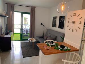 een woonkamer met een tafel en een bank bij Coqueto apartamento ZUA con piscina in Costa Teguise