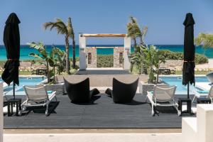 a resort with chairs and a swimming pool at Eden Beachfront Residences & Suites in Kastraki