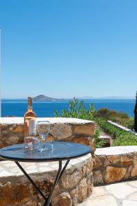 Patmos Exclusive Villas في سكالا: طاولة مع زجاجة وكأسين النبيذ عليها